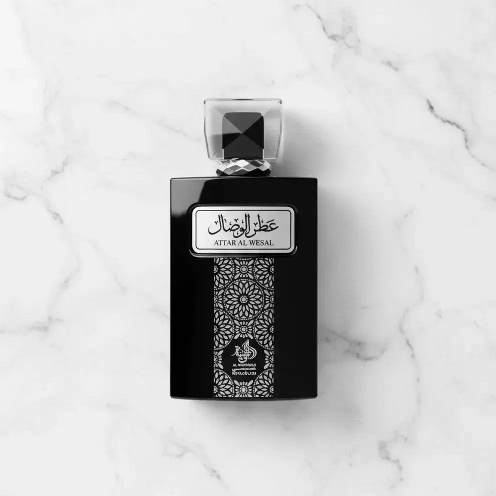 Perfume Attar Al Wesal da Al Wataniah em frasco preto com tampa facetada, fotografado de cima sobre mármore branco