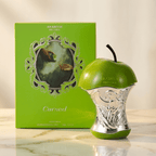 Frasco em formato de maçã do perfume Cursed da Arabiyat Prestige ao lado da caixa verde, sobre superfície de mármore.