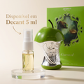 Frasco em formato de maçã prateada e verde do perfume Cursed da Arabiyat Prestige, ao lado da caixa e de um decant de 5ml, com texto "Disponível em Decant 5 ml".