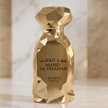 Perfume Mahd Al Dhahab da Arabiyat Prestige em close do frasco dourado facetado, com colunas de mármore ao fundo.