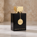 Frasco preto do perfume Club de Nuit Intense feminino da Armaf, com tampa dourada quadrada e pingente medalhão, sobre superfície de mármore.
