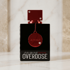 Frasco do perfume Club de Nuit Intense Overdose da Armaf, em vidro preto com tampa vermelha metálica e medalhão pendurado, sobre superfície de mármore.