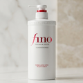 Frasco branco do condicionador Fino Premium Touch com válvula pump, fundo em tons de mármore bege.