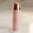 Body Spray Haya, frasco rosa com padrão raiado e tampa rose gold, sobre mármore.