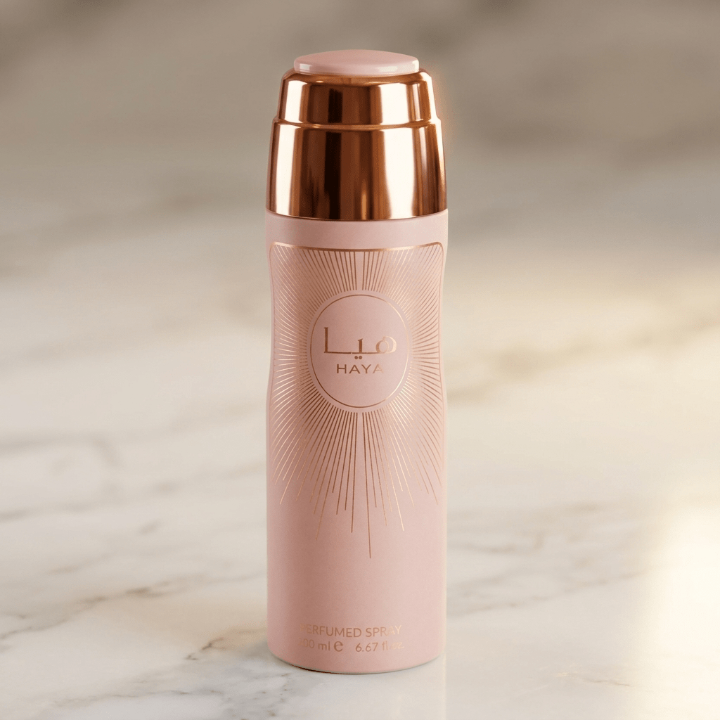 Body Spray Haya, frasco rosa com padrão raiado e tampa rose gold, sobre mármore.