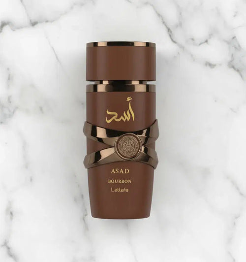 Perfume Asad Bourbon da Lattafa em frasco marrom fotografado de cima sobre mármore branco