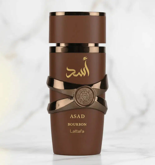 Perfume Asad Bourbon da Lattafa em frasco marrom com faixas metálicas cruzadas, vista frontal sobre mármore