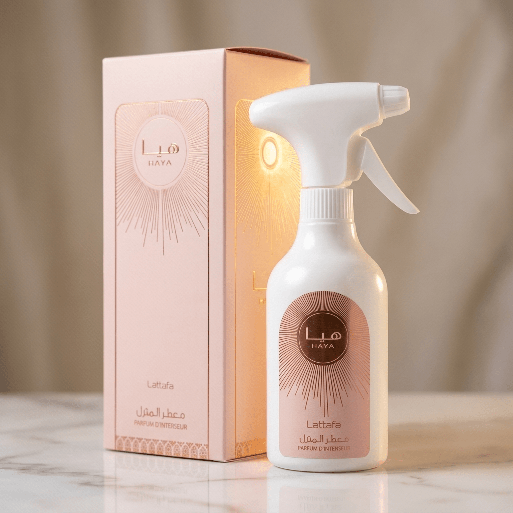 Home Spray Haya Lattafa 450ml, frasco ao lado da caixa rosa com padrão raiado, sobre mármore.