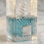 Perfume Khamrah Waha da Lattafa em frasco facetado com líquido azul-turquesa, vista aproximada em ângulo com luz dourada