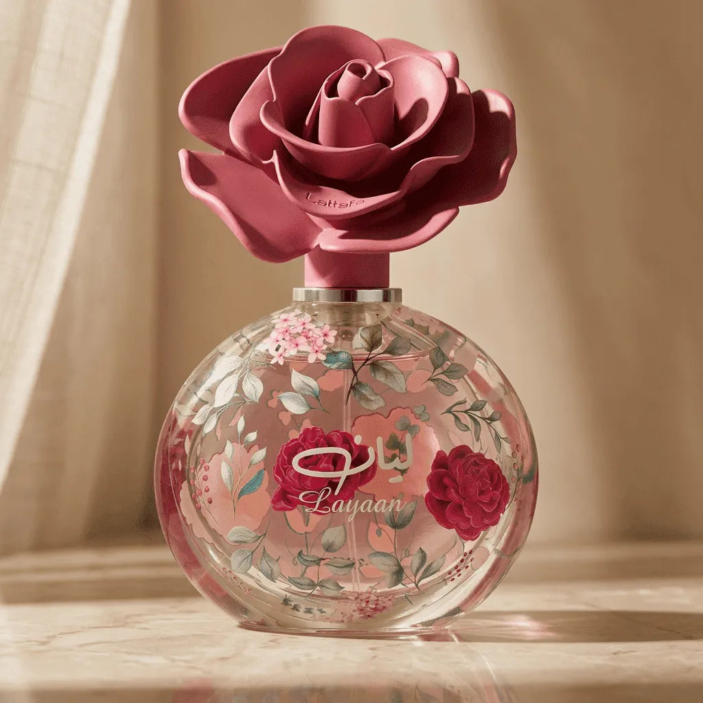 Perfume Layaan da Lattafa em frasco redondo pintado com flores rosa, tampa em formato de rosa, ao fundo cortina bege