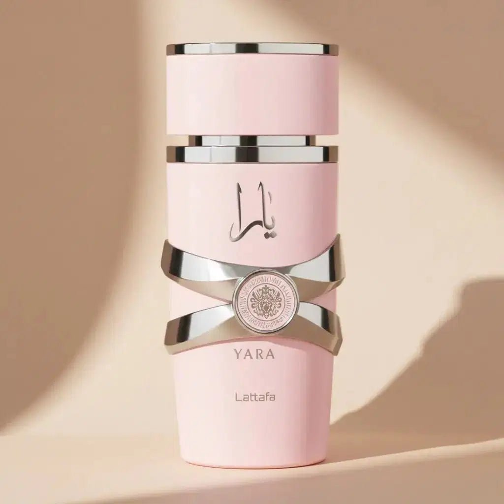 Perfume Yara da Lattafa em frasco rosa com faixas metálicas cruzadas, sobre fundo bege com sombras dramáticas