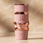 Perfume Yara da Lattafa em frasco rosa com faixas rosé gold cruzadas, sobre fundo desfocado em tons dourados