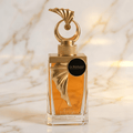 Perfume Malaky da Le Bonheur em frasco de vidro âmbar com tampa dourada em formato de leque, sobre mármore.