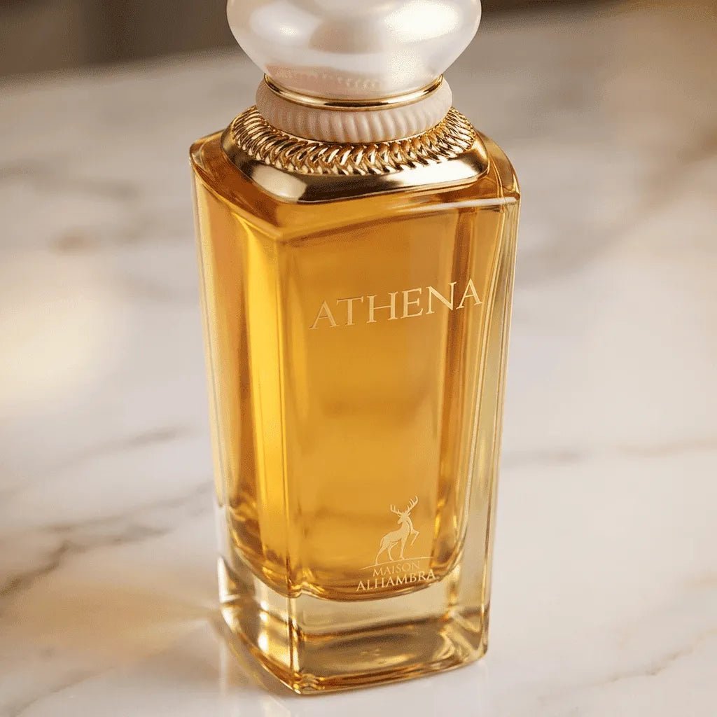 Perfume Athena da Maison Alhambra em frasco facetado âmbar com tampa perolada e detalhes dourados, sobre mármore