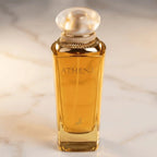 Perfume Athena da Maison Alhambra em frasco facetado âmbar com tampa perolada, vista frontal sobre mármore claro