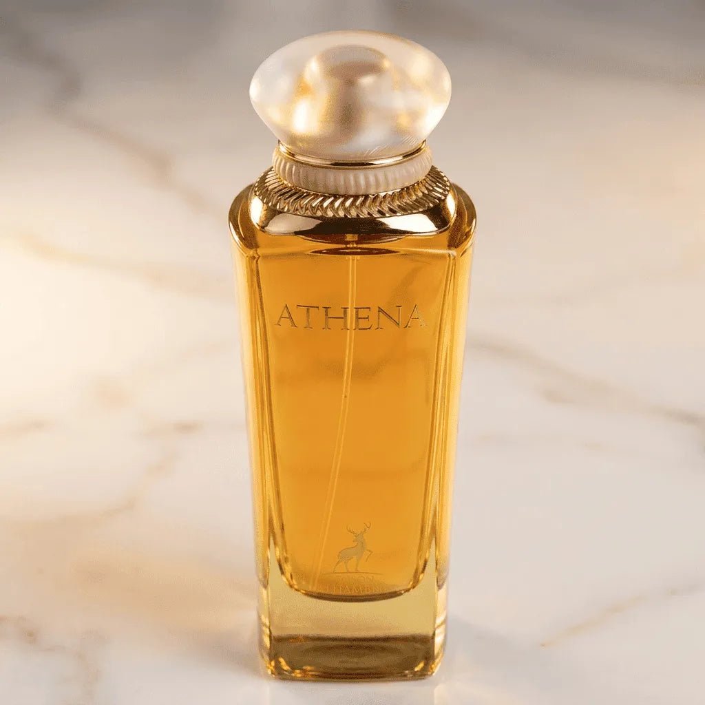Perfume Athena da Maison Alhambra em frasco facetado âmbar com tampa perolada, vista frontal sobre mármore claro