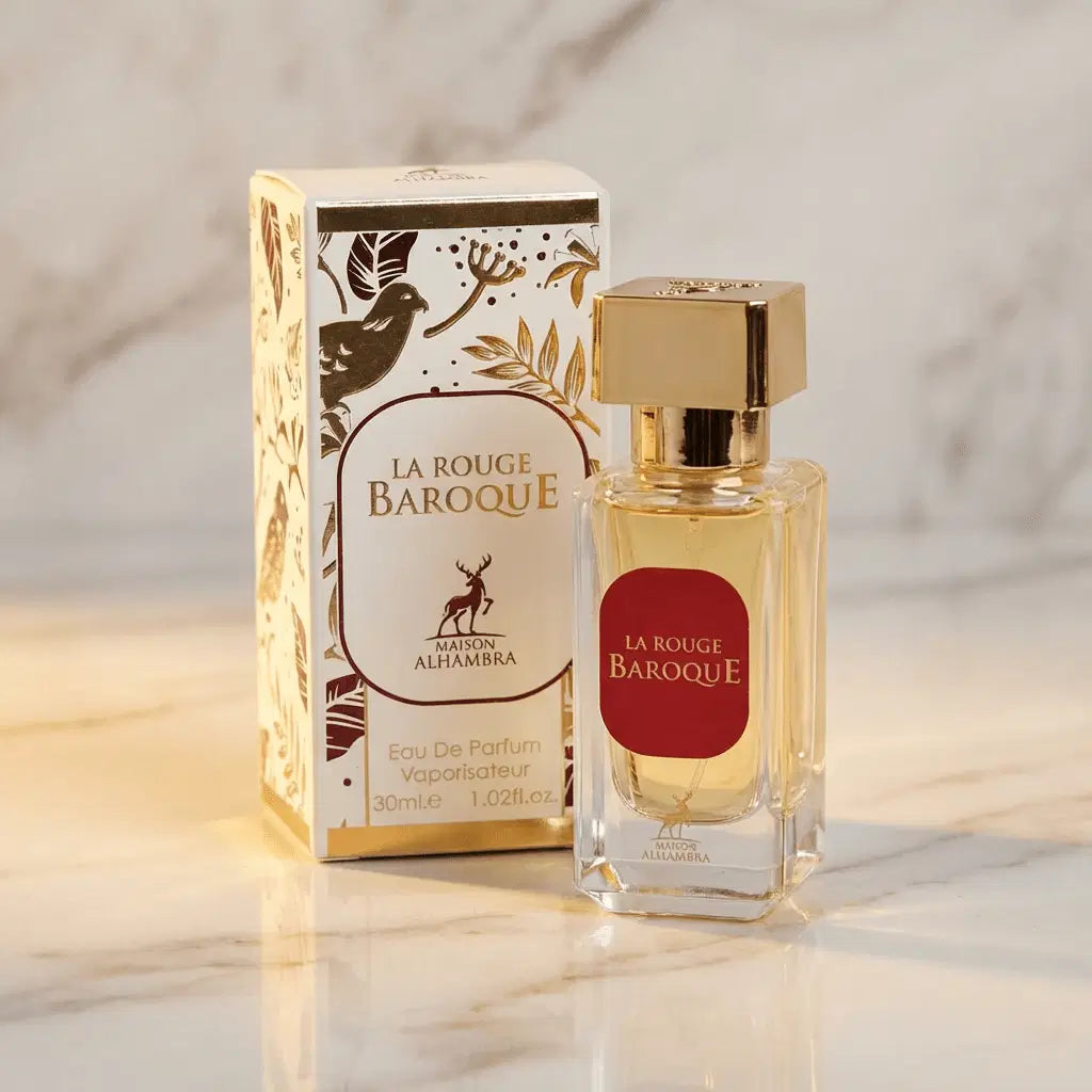 Perfume La Rouge Baroque da Maison Alhambra em frasco facetado âmbar com tampa dourada e rótulo vermelho, ao lado da caixa branca com estampa dourada floral