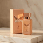 Perfume Olivia da Maison Alhambra 30ml em frasco pêssego ao lado da caixa pêssego original, sobre mármore