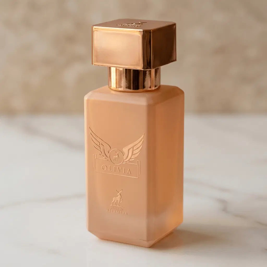 Perfume Olivia da Maison Alhambra em frasco pêssego translúcido com gravação em relevo, sobre mármore claro