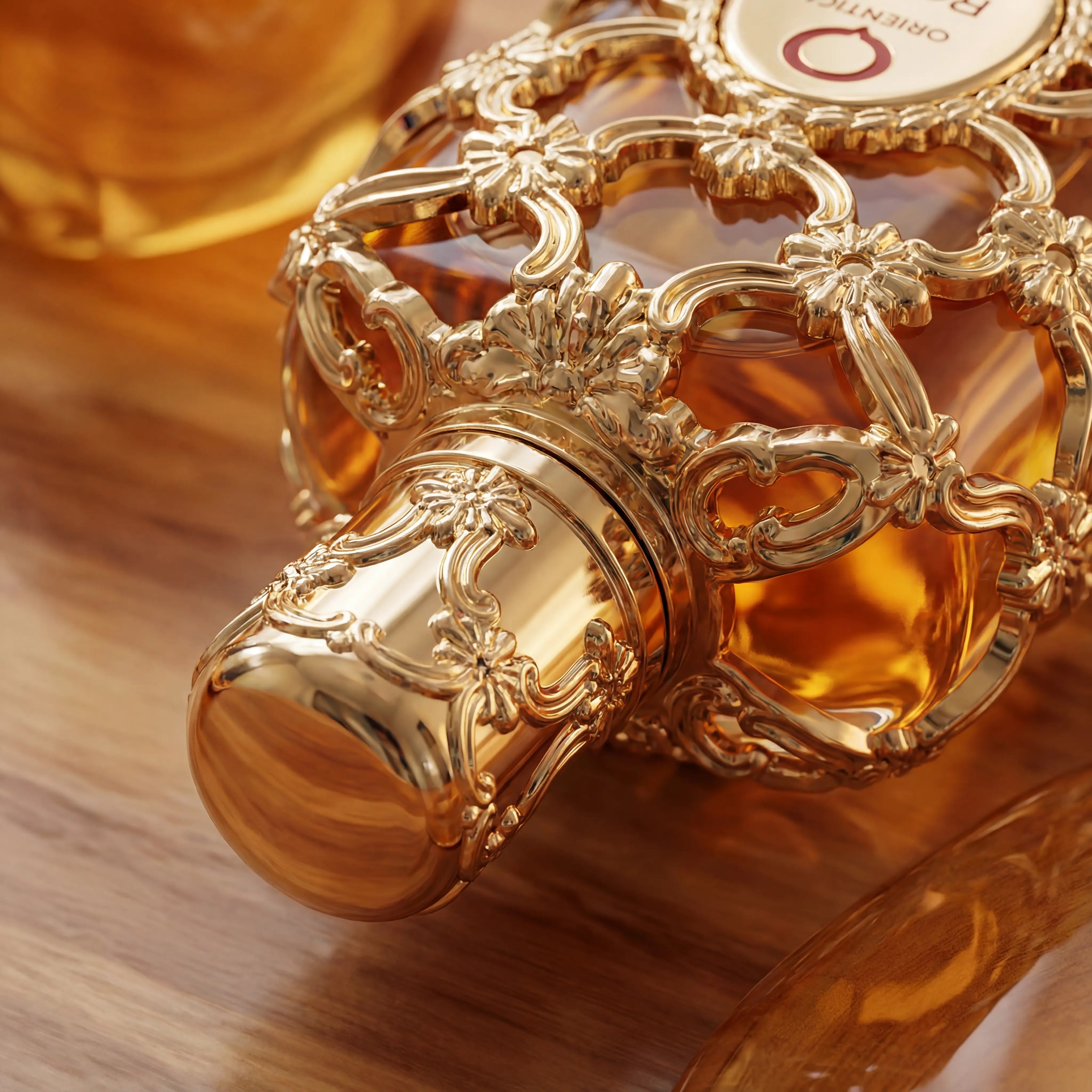 Detalhe da tampa dourada ornamentada do perfume Exclusive Royal Amber da Orientica, sobre madeira.