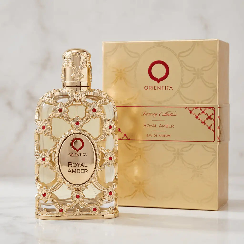 Perfume Exclusive Royal Amber da Orientica ao lado da caixa dourada, sobre mármore claro.