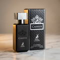 Frasco de perfume Cassius da Maison Alhambra, preto e dourado, ao lado da caixa do produto sobre marmore.
