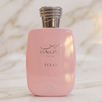 Frasco rosa do perfume Hawas Éclat for Her em vista frontal, tampa prateada com detalhes trançados, sobre fundo de mármore.