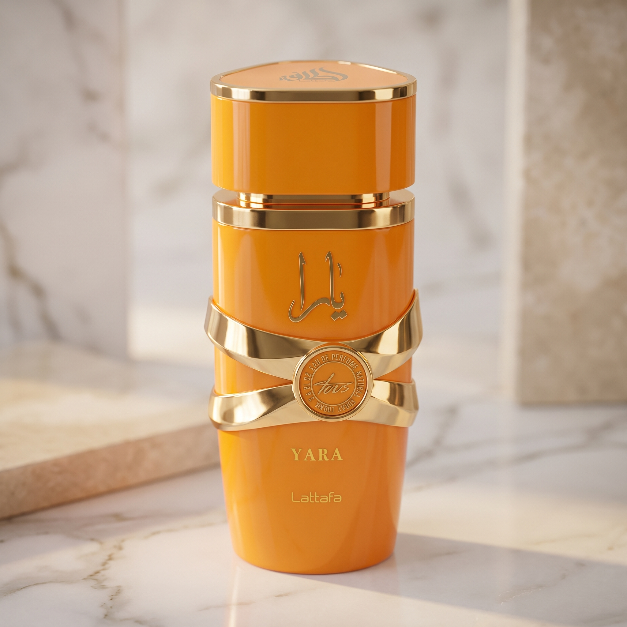 Frasco de perfume Yara da Lattafa, laranja com detalhes dourados em formato de laco, sobre superficie de marmore.