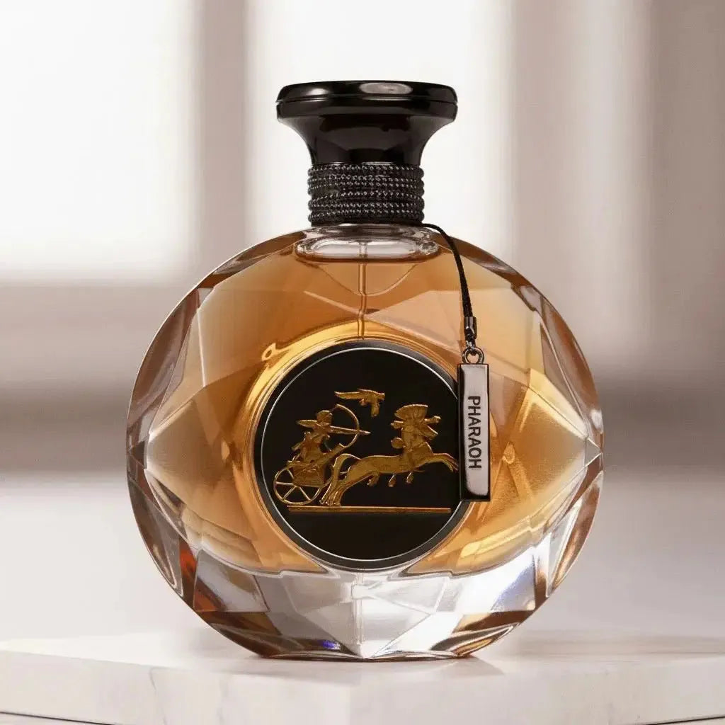 Perfume Pharaoh em frasco redondo de cristal facetado com líquido âmbar, medalhão dourado com carruagem egípcia