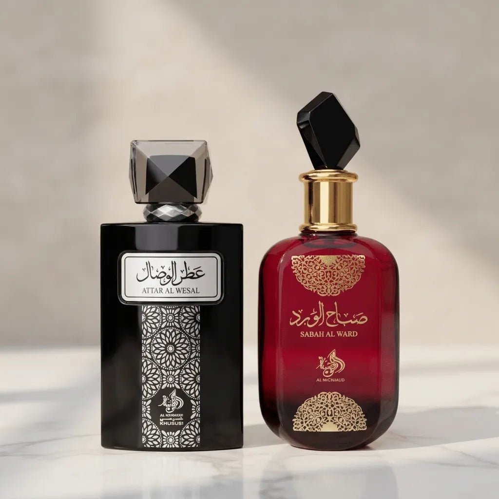 Perfumes Attar Al Wesal em frasco preto e Sabah Al Ward em frasco vermelho, ambos com tampas facetadas pretas, lado a lado sobre mármore