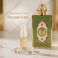Perfume Queen of Arabia em frasco dourado com padrão em mosaico verde e vermelho, tampa em formato de coroa cravejada, ao lado de decant de 5ml com banner promocional