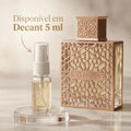 Perfume Rayhaan em frasco cúbico rosé com padrão vazado geométrico, ao lado de decant de 5ml com banner promocional