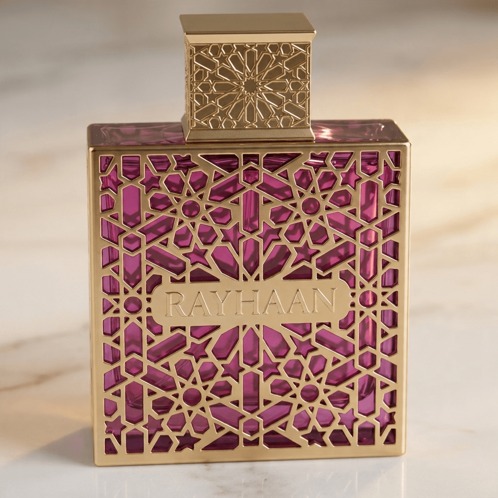 Perfume Rayhaan em frasco dourado com padrão arabesco vazado e gemas rosa, tampa quadrada a jogo.