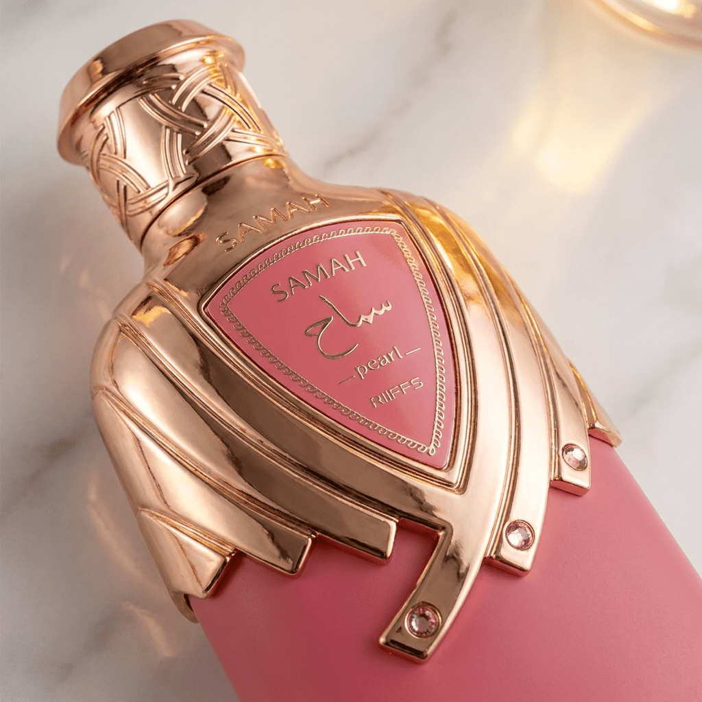 Detalhe do frasco rosa do perfume Samah Pearl, com brasão dourado cravejado e tampa metálica trançada.