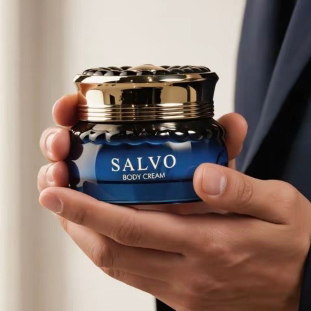 Creme corporal Salvo em pote de vidro azul com tampa dourada e detalhe canelado, segurado na mão.