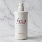 Frasco branco do shampoo Fino Premium Touch em pé, vista frontal, sobre fundo de mármore claro.