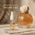 Perfume Vanilla Royal em frasco âmbar formato abóbora com tampa em concha, ao lado de decant de 5ml com banner promocional